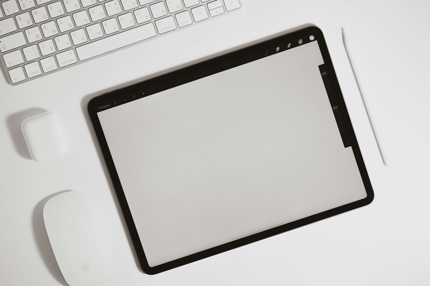 Tablette posée à côté d'un clavier sur une table blanche